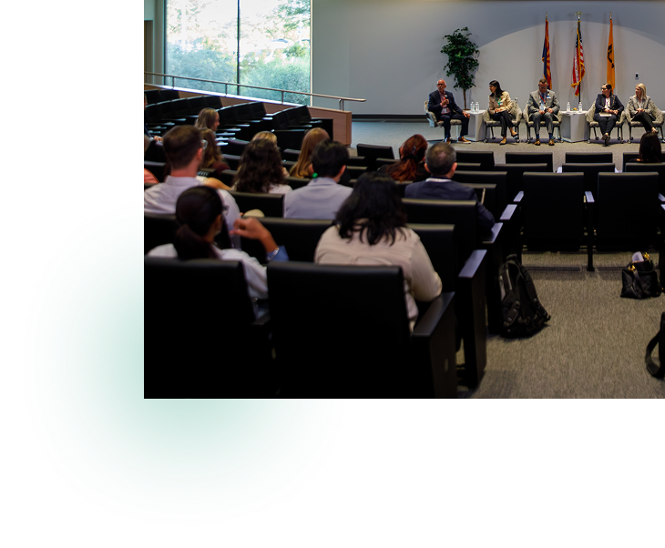 A panel discussion in a conference room with an audience.